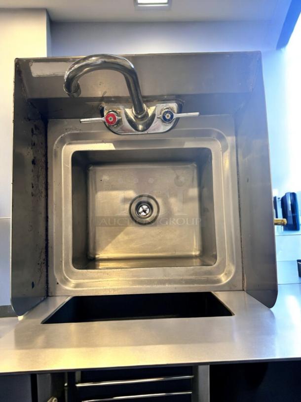 Stainless steel wall-mount hand sink with faucet, in excellent condition. Fully tested and cleaned. Features hot and cold handles.