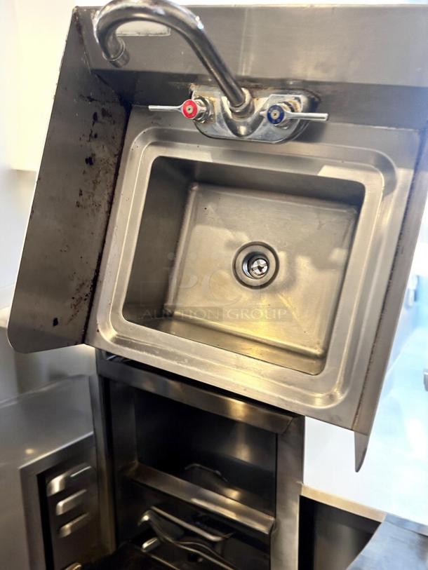 Stainless steel wall-mount hand sink with faucet, excellent condition, fully tested and cleaned, featuring hot and cold handles.