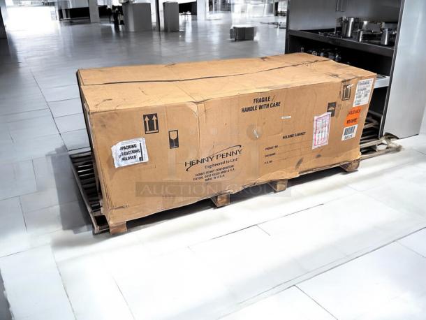 Brand new Henny Penny HHC900.24 heated holding cabinet, factory sealed in box, on a pallet with shipping labels visible.