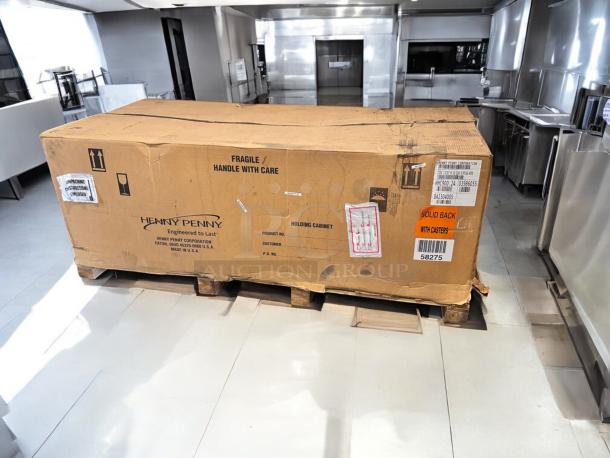 Factory-sealed Henny Penny HHC900.24 heated holding cabinet in cardboard packaging, labeled "Solid Back with Casters," 120V.