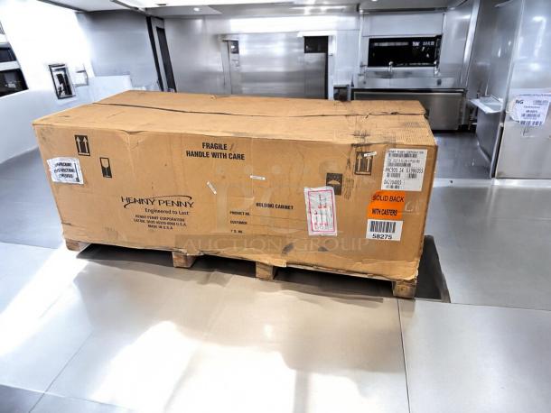 Brand new Henny Penny HHC900.24 heated holding cabinet in factory-sealed box. Features solid back, casters, 120V. Shipping labels visible.