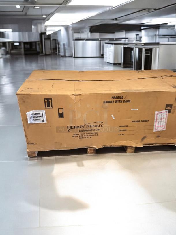 Brand new Henny Penny HHC900.24 heated holding cabinet in sealed box, featuring "Handle with Care" and brand labels.