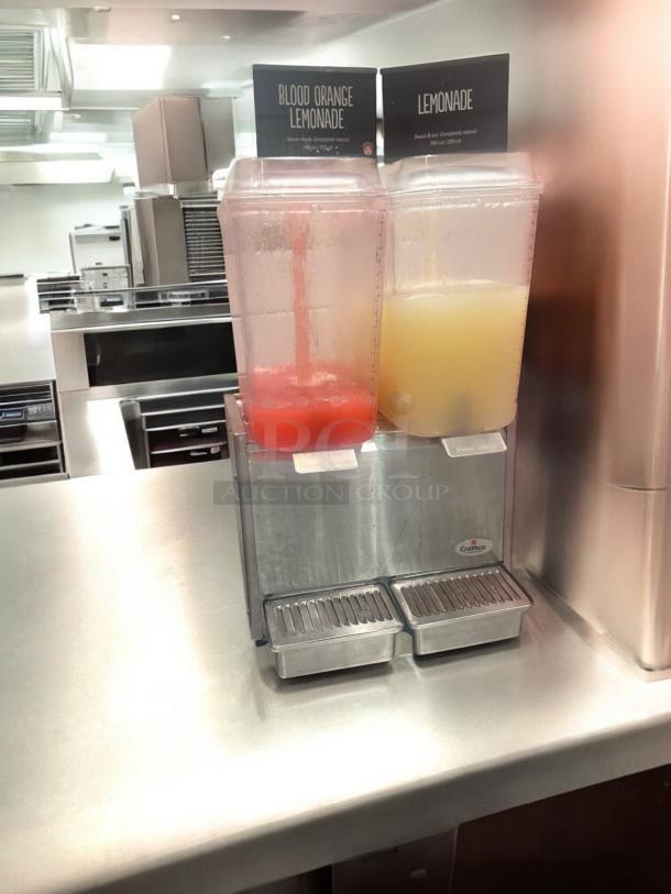 Crathco D25-3 dual tank cold beverage dispenser in excellent condition, fully tested, labels: Blood Orange Lemonade, Lemonade.