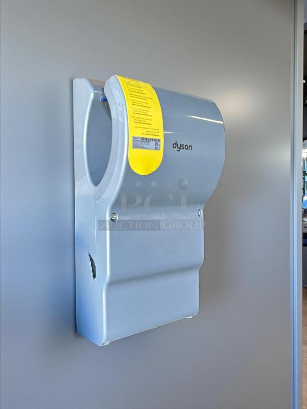 Dyson Airblade hand dryer, silver, model 13043-01, in excellent condition, wall-mounted with yellow instruction label.