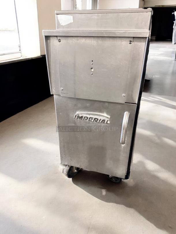 Stainless steel kitchen appliance with "Imperial" logo on the front, positioned on casters in a sunlit room.
