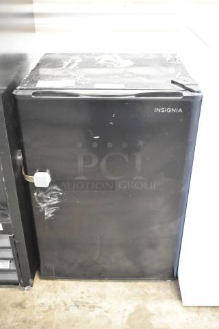 Insignia NS-CF26BK9 Mini Cooler, black, 115 volts, 1 phase. Minor scratches and wear visible on the surface.