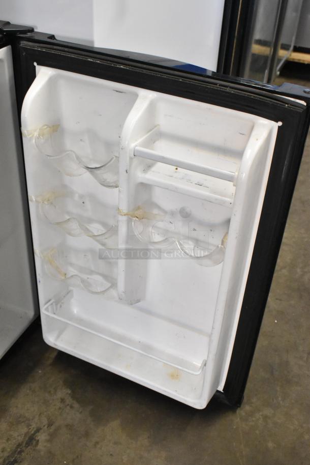 Insignia NS-CF26BK9 mini cooler, open door showing interior storage racks, minor wear visible. 115 Volts, 1 Phase.