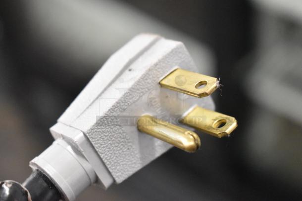 Close-up of a three-prong electrical plug with brass contacts, part of a True GDM-41SL-48-HC-LD cooler.