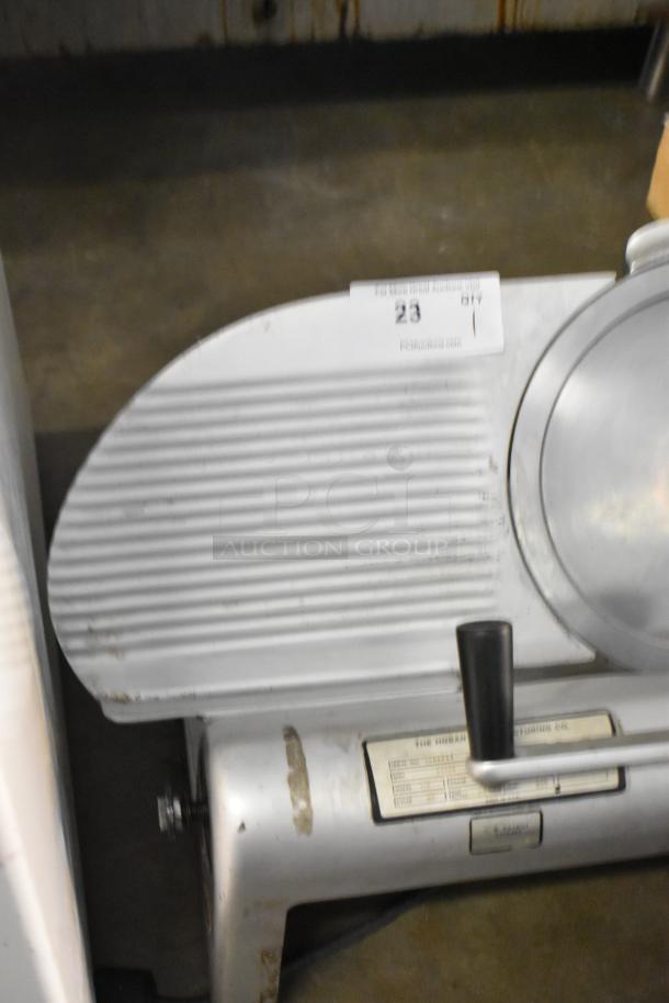 Hobart 1612 metal commercial meat slicer, countertop model. Features a serrated cutting blade, sturdy handle, and power label.