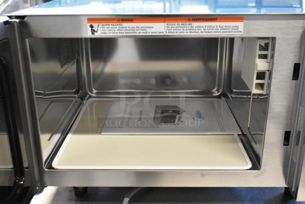 2024 Midea 1025FOA stainless steel countertop microwave, commercial use, open door with safety warning sticker visible.