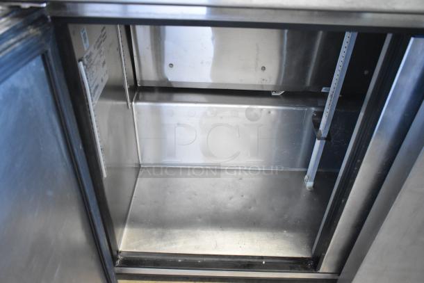 True TUC-48F-LP stainless steel undercounter freezer, 2-door, on casters, 115V, 1 phase, clean interior, visible shelving.