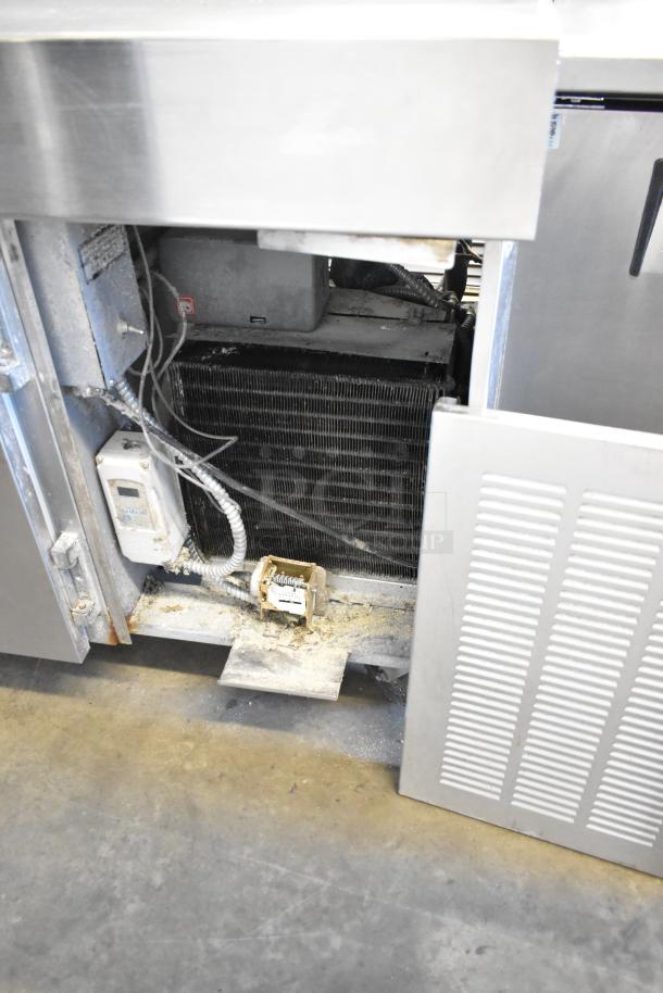 Stainless steel commercial pizza prep table, visible internal components, on commercial casters, 115 volts, 1 phase.