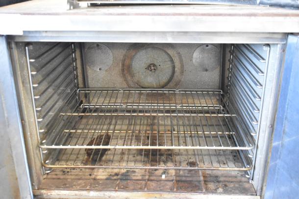 Blodgett stainless steel gas convection oven with solid doors, metal oven racks, thermostatic controls, and metal legs.