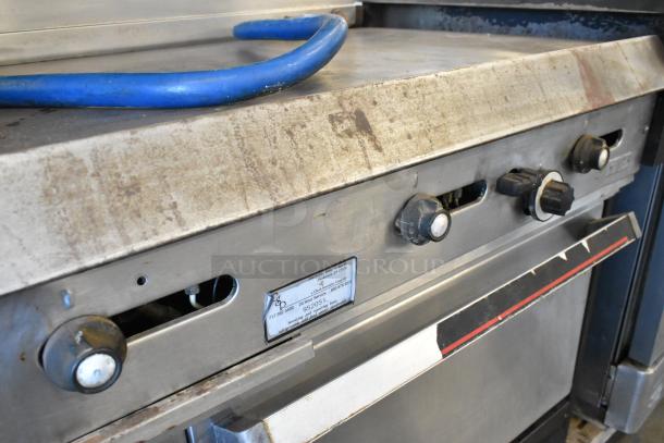 Garland metal commercial gas griddle with two sections, two ovens, over shelf, and back splash. Used condition.