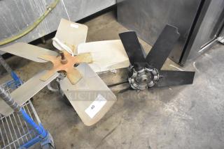 Two industrial fans, one with silver blades and the other with black, on a metal floor. Visible label: "40 QTY x2."