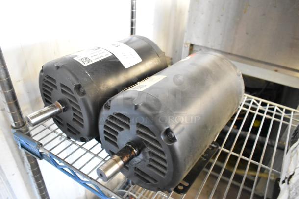 Two Baldor motors, black, 460 volts, 3 phase, on metal shelf, visible labels with electrical specs.