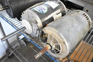 Two industrial motors: Marathon WG55T8O15516A and US Motors J63WZBKH-0246, 208-230/460V, 3-phase, on a metal shelf.