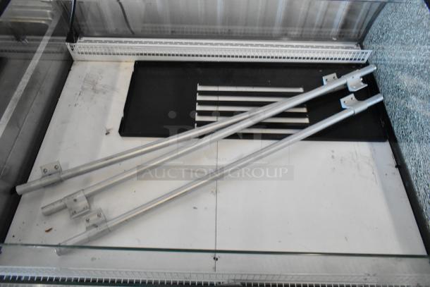 Econocold OM-IRSSCG island fridge with curved glass, commercial casters; interior view with shelves and mounting bars.