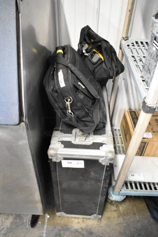 Four black bags including a DTE FS-100 DVCPro, each with various contents, placed on and near a hard protective case.