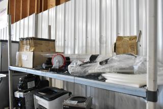 Auction shelf lot with commercial casters, flared coupe glass box, and various sealed items. Some boxes labeled "USA."