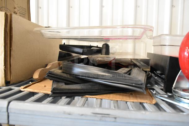 Assorted auction lot with commercial casters, flared coupe glass, and rubber seals stacked on a shelf.