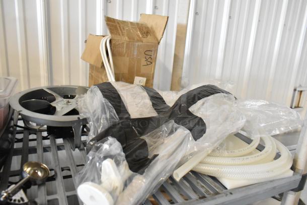 Tiered lot of miscellaneous items including commercial casters, flared coupe glass, and seals on a metal shelf. Visible packaging.
