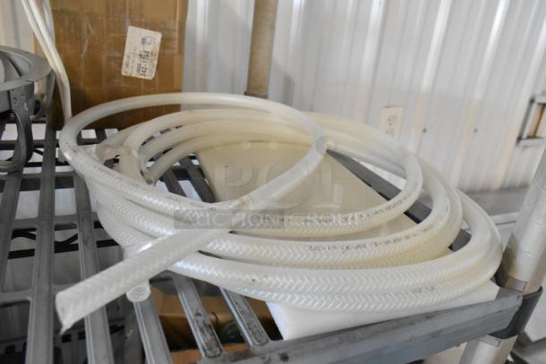 Tier lot with a coiled flexible hose on a metal shelf, visible industrial fittings in background. Signs of moderate wear.