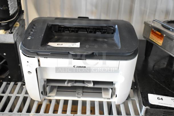 Canon F166500 printer, monochrome model, visible scuffs, front paper tray open, auction tag marked "62", function condition unknown.