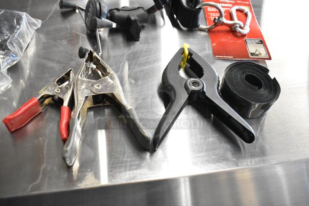 Two boxes with Z Finder Pro Kit and clamps, including metal and plastic clamps, roll of black tape, on steel table.