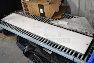 White cutting board, rectangular, with slight wear. Placed on metal shelving unit. Auction tag "68" visible.