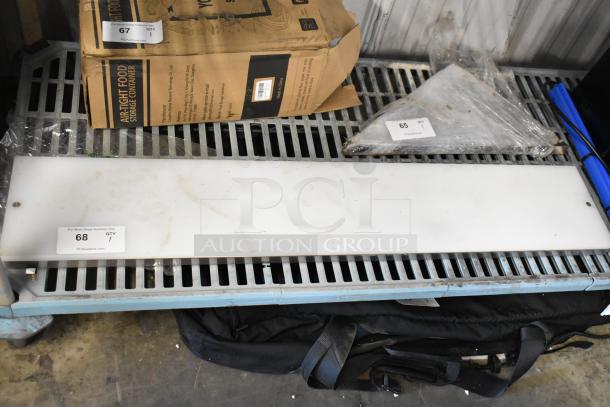 White cutting board with a slightly worn surface, labeled "68, QTY 1" from PCIAuctions.com, resting on a metal shelf.