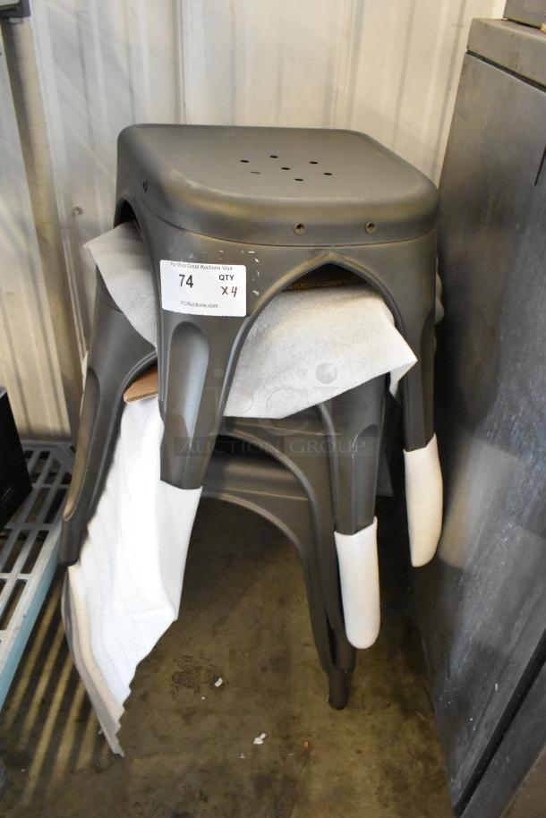 Four metal gray Tolix style stools, stackable, industrial design. Includes label showing quantity and auction info.