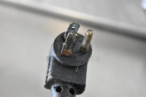 Close-up of a plug from the True TSSU-48-12 commercial prep table, showing worn prongs and signs of wear.
