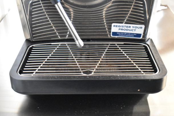Brand new metal commercial espresso machine with steam wand, scratch and dent condition. Features "Register Your Product" label.
