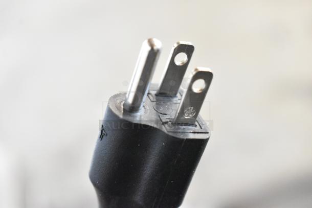 Close-up of a power plug from a commercial countertop espresso machine. Brand new with visible scratches and dents.