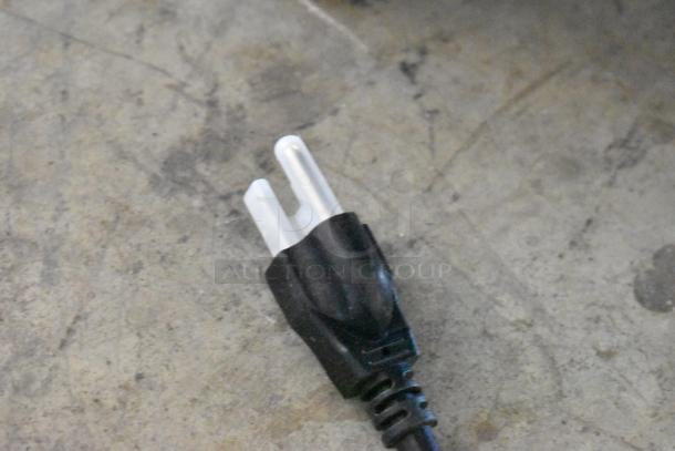 Close-up of a black electrical plug for the 2025 Mahlkonig EK43 coffee grinder, showing standard prongs.
