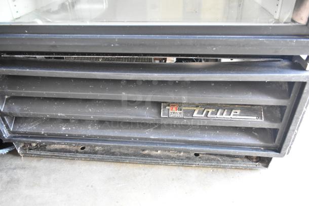 True GDM-12 cooler, black metal, single door, with poly-coated racks. 115 volts, 1 phase. Truel logo visible. Used condition.