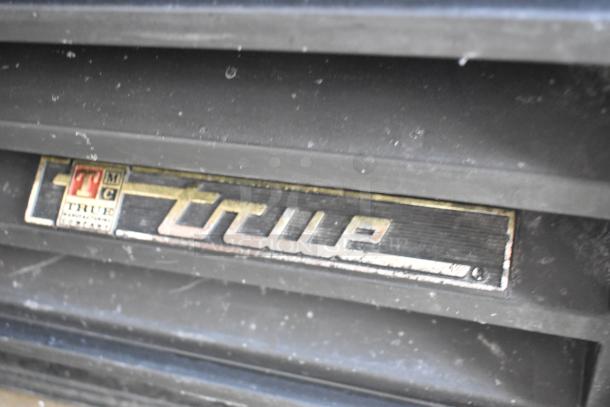 True GDM-12 commercial cooler label close-up, highlighting brand and model details on metal casing.