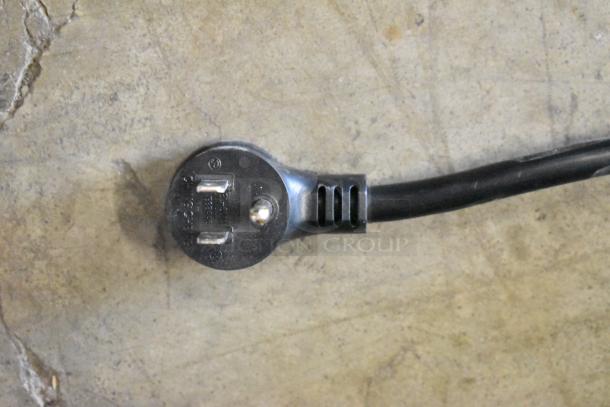 Close-up of a 3-prong plug compatible with the 2020 True GDM-26-HC cooler, showing prongs and cable on a concrete surface.