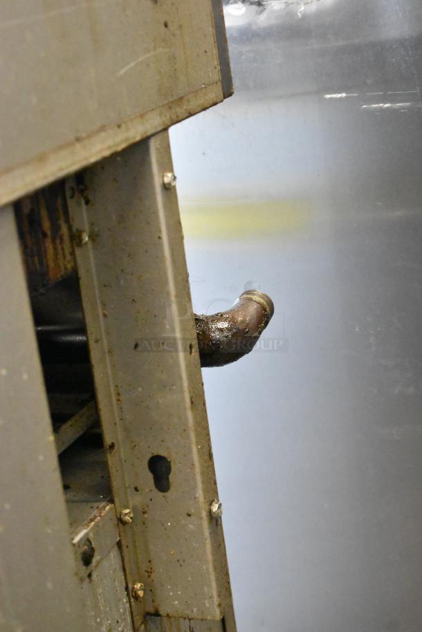 Close-up of a Black Diamond GR-6024G/NG gas range showing a pipe and metal panel with screws, indicating industrial use.