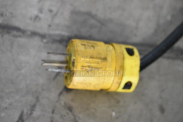 A close-up of a yellow industrial power plug with a few visible prongs, used for commercial equipment.