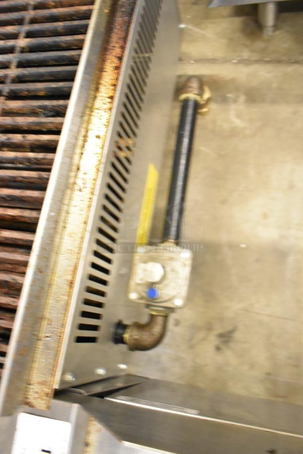 Qualite QLEC-24/NG stainless steel charbroiler, natural gas powered, 60,000 BTU, visible piping, slight wear.