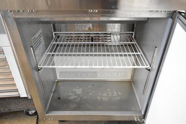 2023 Coldline SP-27 stainless steel prep table interior with wire shelf, clean, showing slight wear. Model label visible inside.