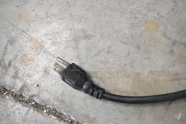 A close-up image of a power cord plug on a concrete floor, possibly from the Coldline SP-27 prep table.