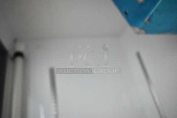 Blurry image of interior with metallic and white surfaces; no distinct details of item visible.