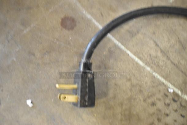 Power cord of a True GDM-05 metal mini cooler merchandiser, 115 volts, 1 phase, shown on a concrete floor.