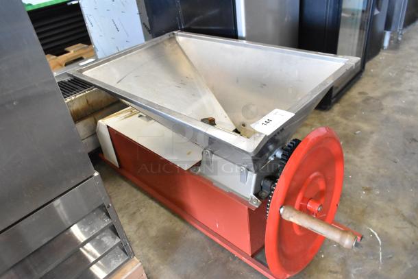 Metal commercial countertop cookie dough depositor with red base, large hopper, and hand crank. Visible label reads "144."