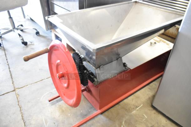 Metal commercial countertop cookie dough depositor with red hand crank and gears. Appears in good condition.
