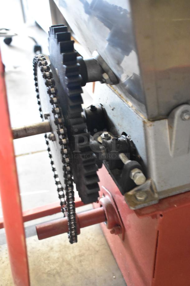Metal commercial countertop cookie dough depositor with visible gear mechanism and chain drive. Rugged build, used condition.