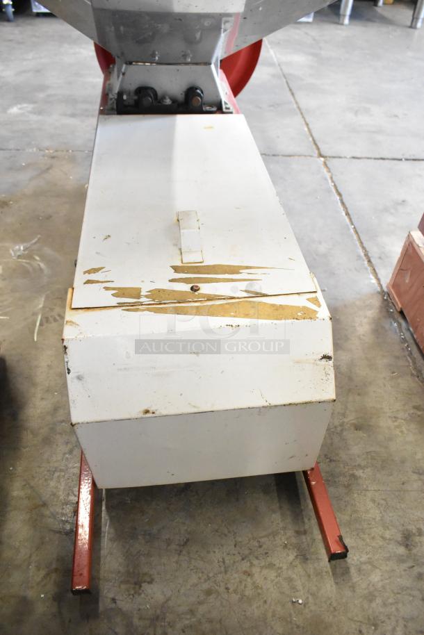 Metal commercial countertop cookie dough depositor, showing wear on the surface, mounted on red legs. Ideal for bakeries.
